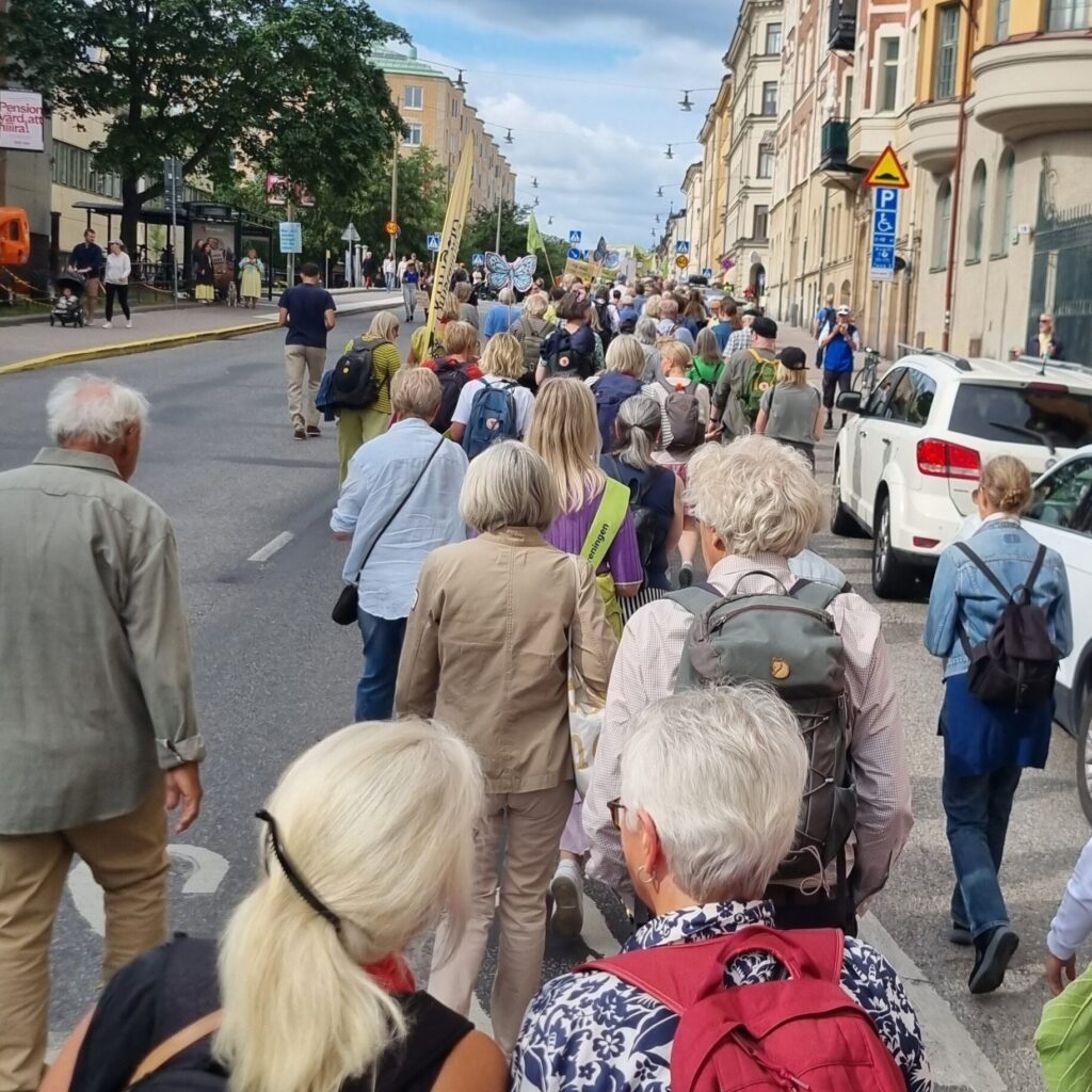 Människor i ett demonstration som går längs med en gata.